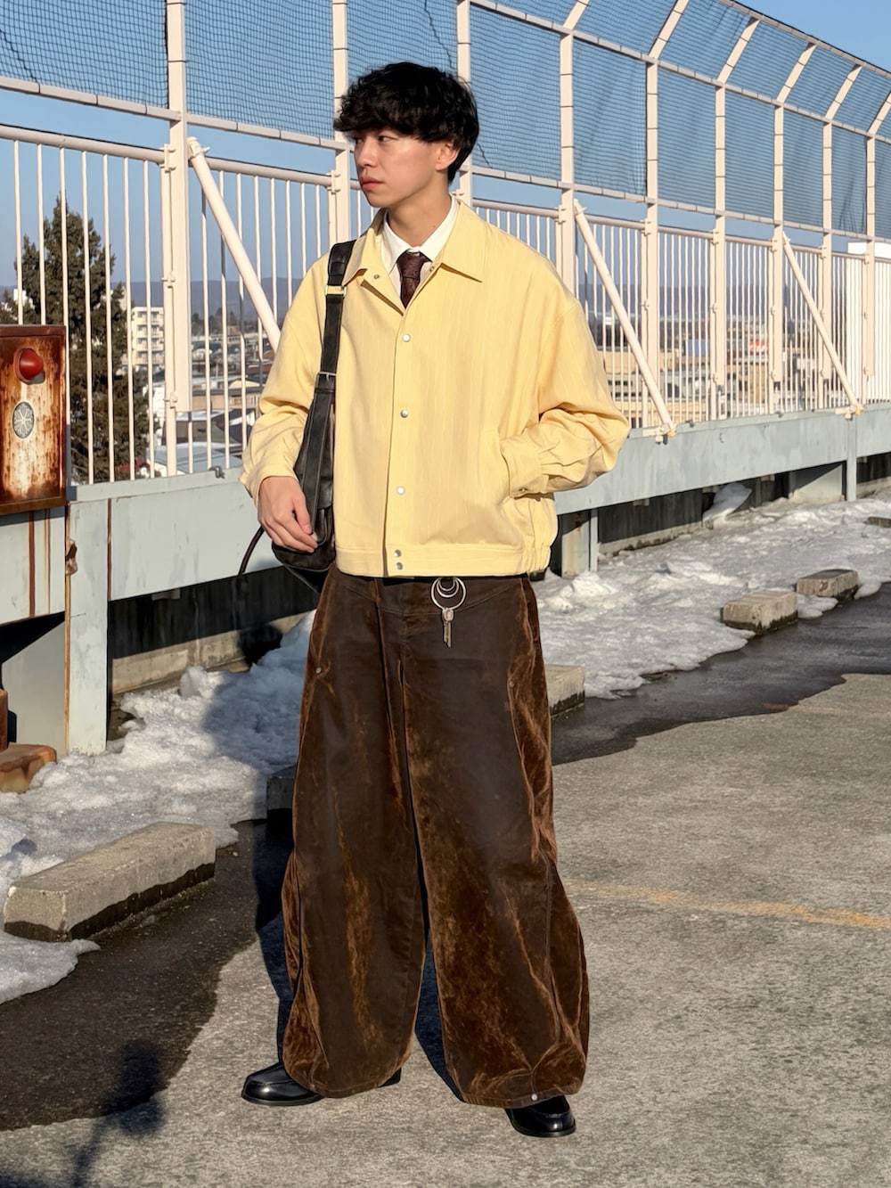 イエロー系のブルゾン、ホワイト系のシャツ/ブラウス、ブラウン系のデニムパンツを着用したメンズの冬コーディネートの3枚目の写真