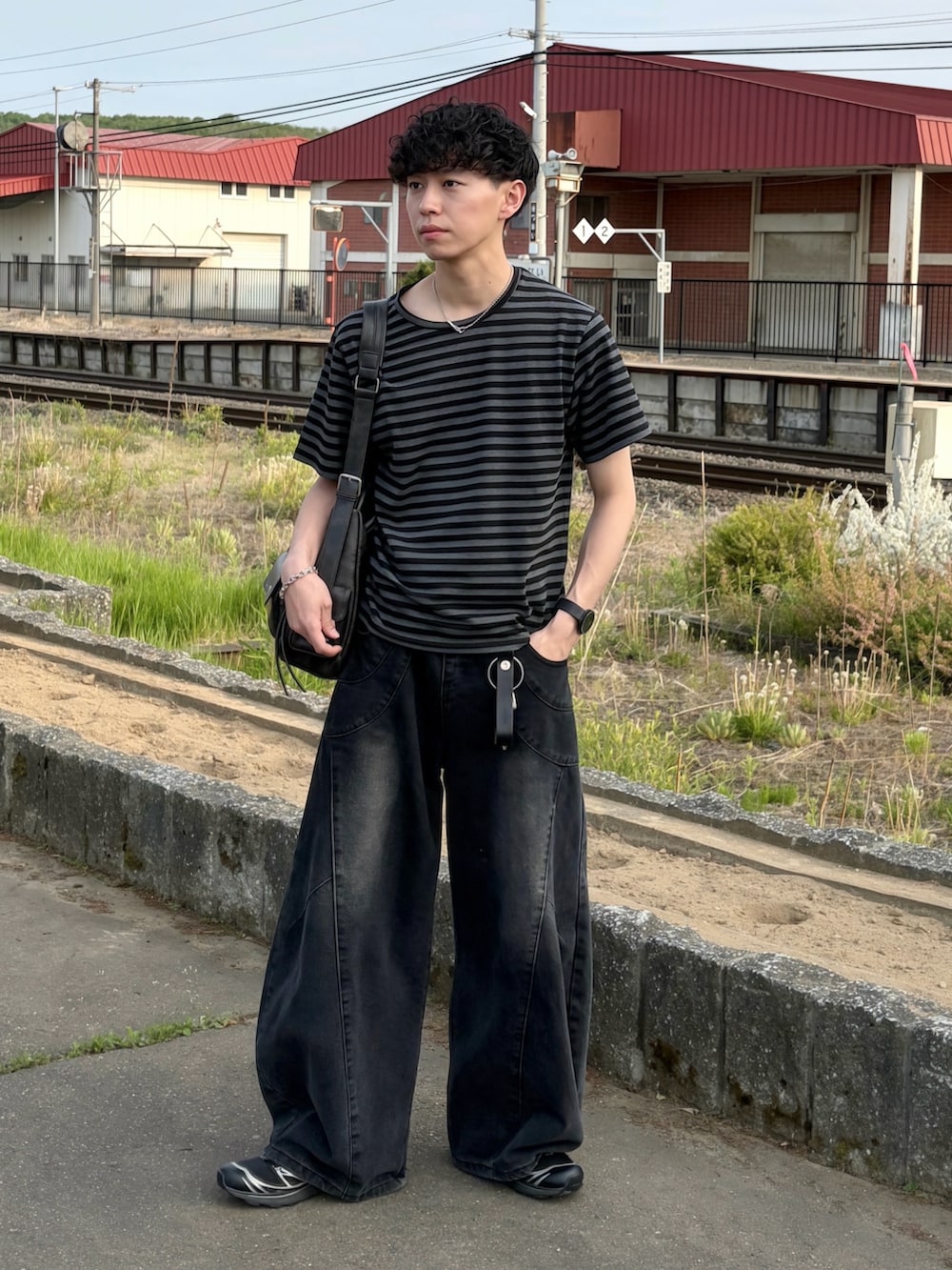 ブラック系のTシャツ/カットソー、ブラック系のデニムパンツ、ブラック系のスニーカーを着用したメンズの春コーディネートの2枚目の写真