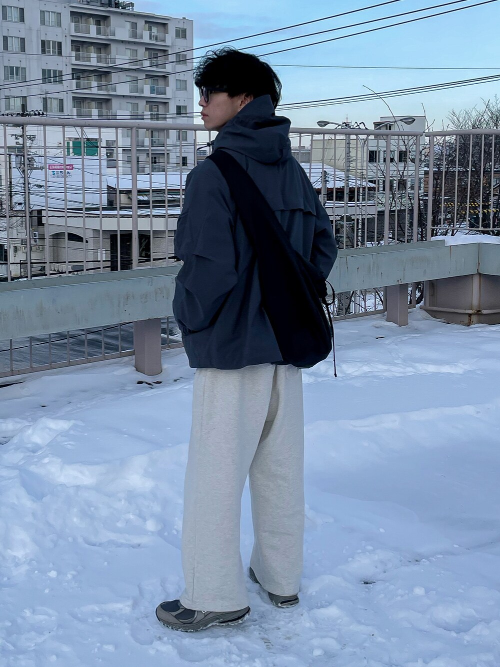 グレー系のマウンテンパーカー、ホワイト系のスウェットパンツ、グレー系のスニーカーを着用したメンズの冬コーディネートの4枚目の写真