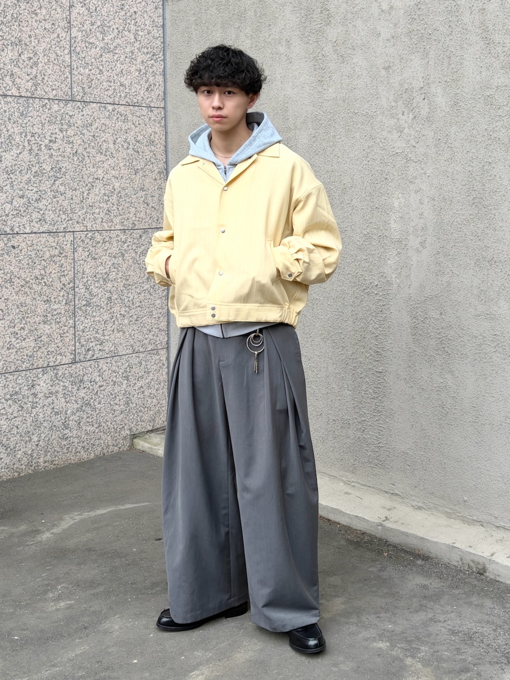 イエロー系のブルゾン、グレー系のスラックス、ブラック系のローファーを着用したメンズの冬コーディネートの2枚目の写真