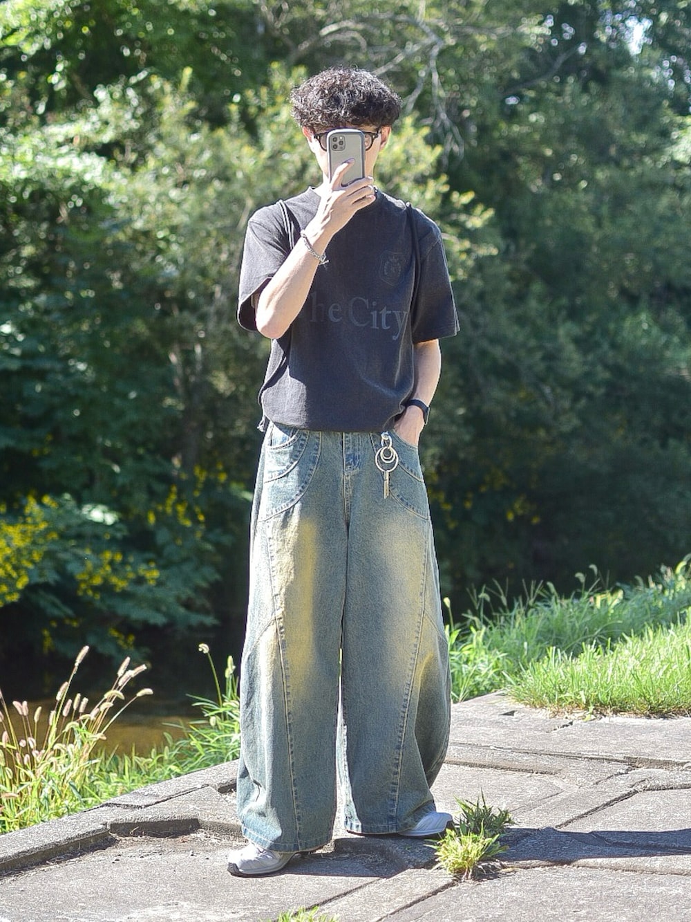 ブルー系のデニムパンツ、グレー系のスニーカー、ブラック系のTシャツ/カットソーを着用したメンズの夏コーディネートの2枚目の写真