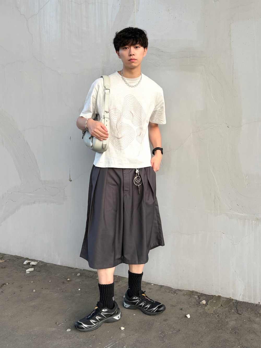ホワイト系のTシャツ/カットソー、グレー系のスラックス、グリーン系のショルダーバッグを着用したメンズの夏コーディネートの3枚目の写真