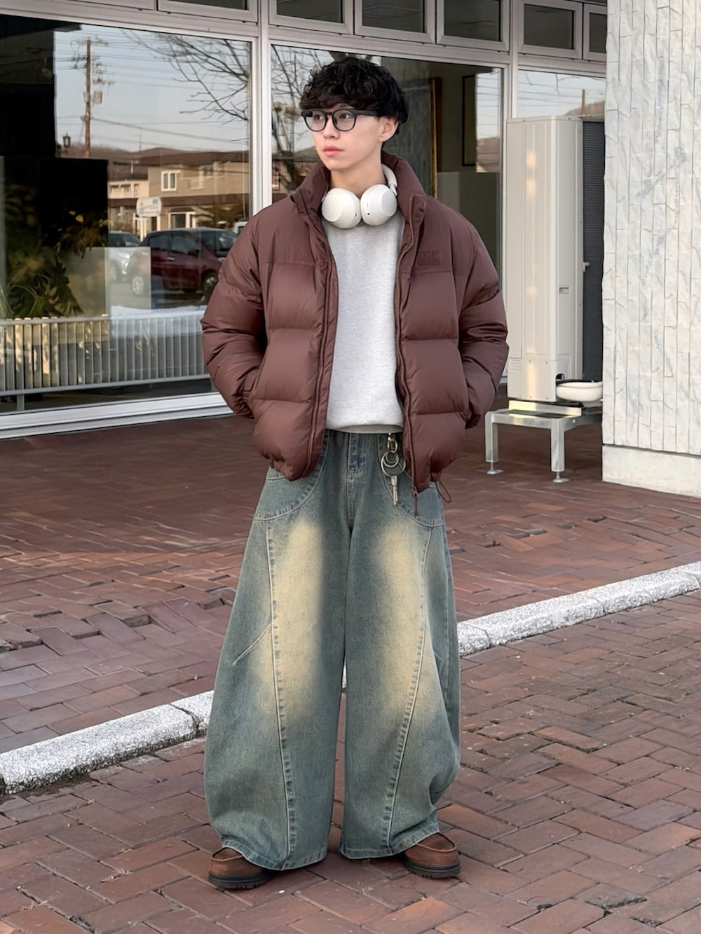 グレー系のスウェット、ブラウン系のダウンジャケット/コート、ブルー系のデニムパンツを着用したメンズの冬コーディネートの2枚目の写真