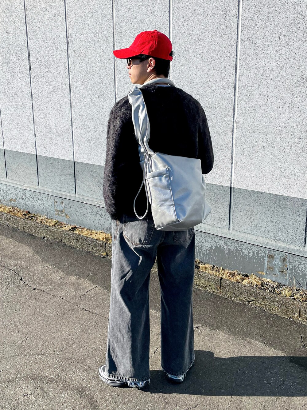 グレー系のニット/セーター、ブラック系のデニムパンツ、シルバー系のショルダーバッグを着用したメンズの冬コーディネートの3枚目の写真