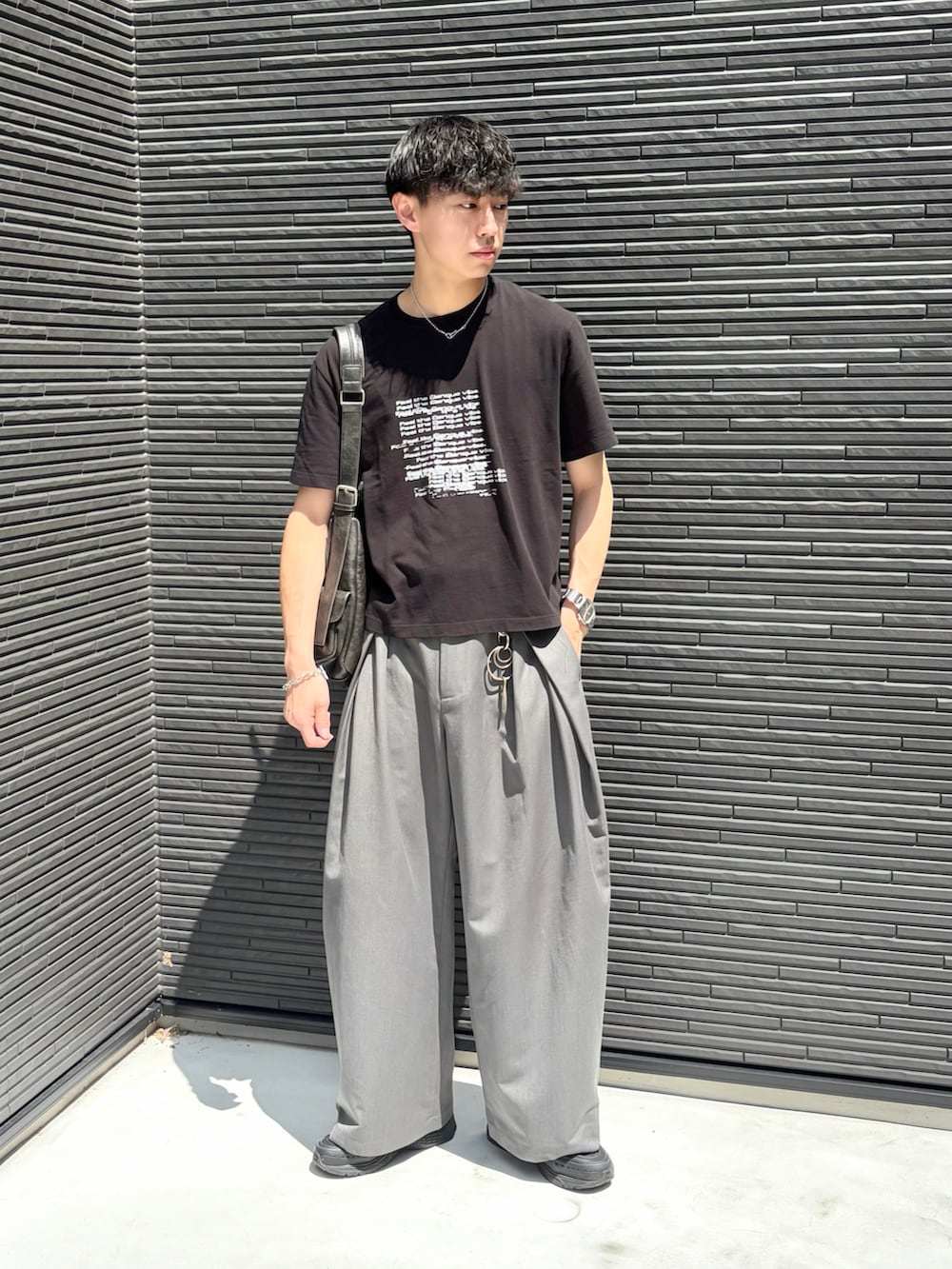 ブラック系のTシャツ/カットソー、グレー系のスラックス、ブラック系のショルダーバッグを着用したメンズの夏コーディネートの2枚目の写真