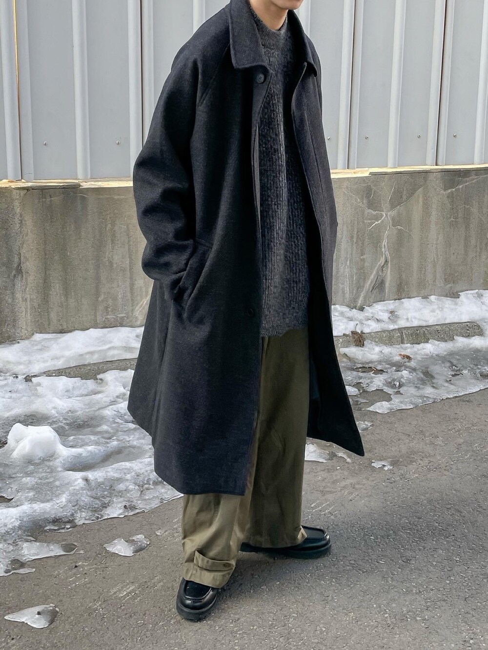 グレー系のニット/セーター、グレー系のステンカラーコートを着用したメンズの冬コーディネートの2枚目の写真