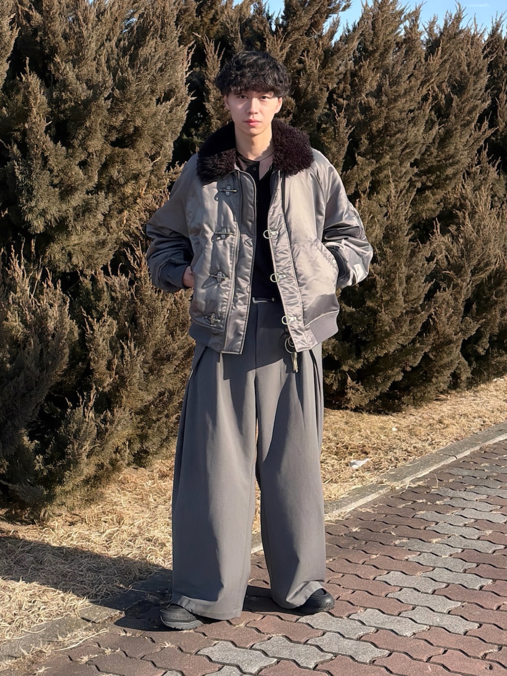 グレー系のブルゾン、ブラック系のTシャツ/カットソー、グレー系のスラックスを着用したメンズの冬コーディネートの2枚目の写真