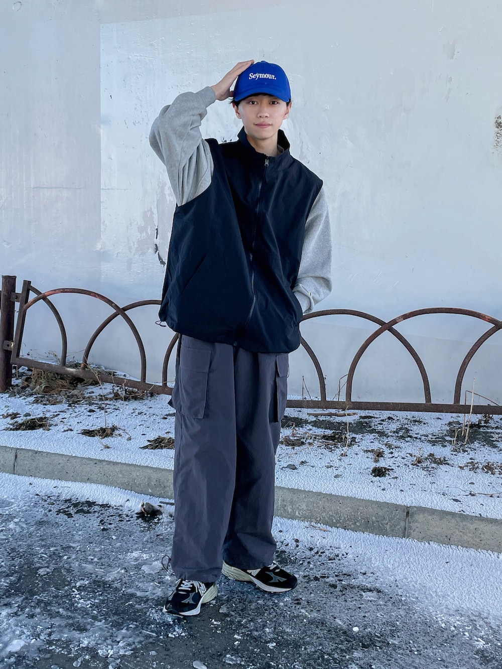 グレー系のカーゴパンツ、ブラック系のベスト、ブラック系のシューズを着用したメンズの冬コーディネートの2枚目の写真