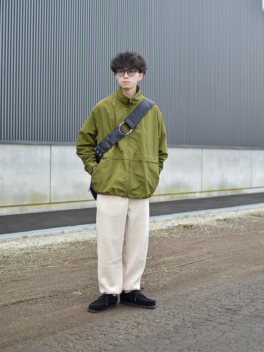 グリーン系のナイロンジャケット、ホワイト系のパンツ、ブラック系のショルダーバッグを着用したメンズの冬コーディネートの4枚目の写真