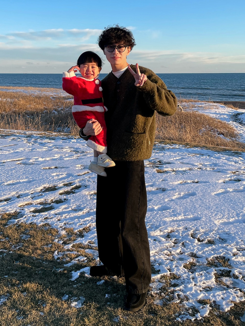 グリーン系のニット/セーター、グレー系のTシャツ/カットソー、ブラック系のデニムパンツを着用したメンズの冬コーディネートの5枚目の写真