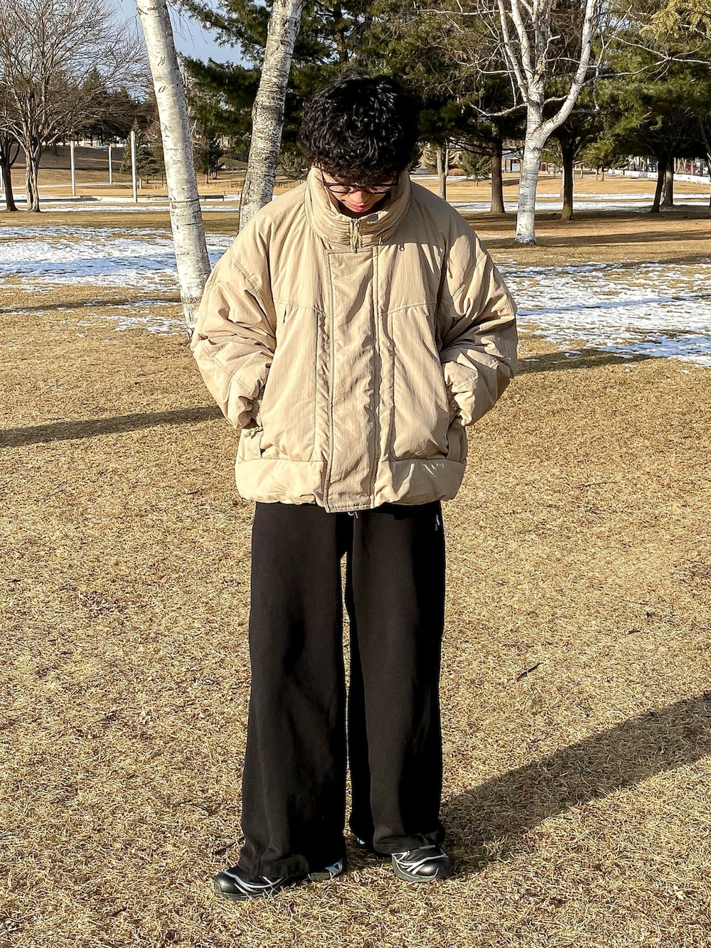 グリーン系のダウンジャケット/コート、ブラック系のスウェットパンツ、ブラック系のスニーカーを着用したメンズの冬コーディネートの3枚目の写真