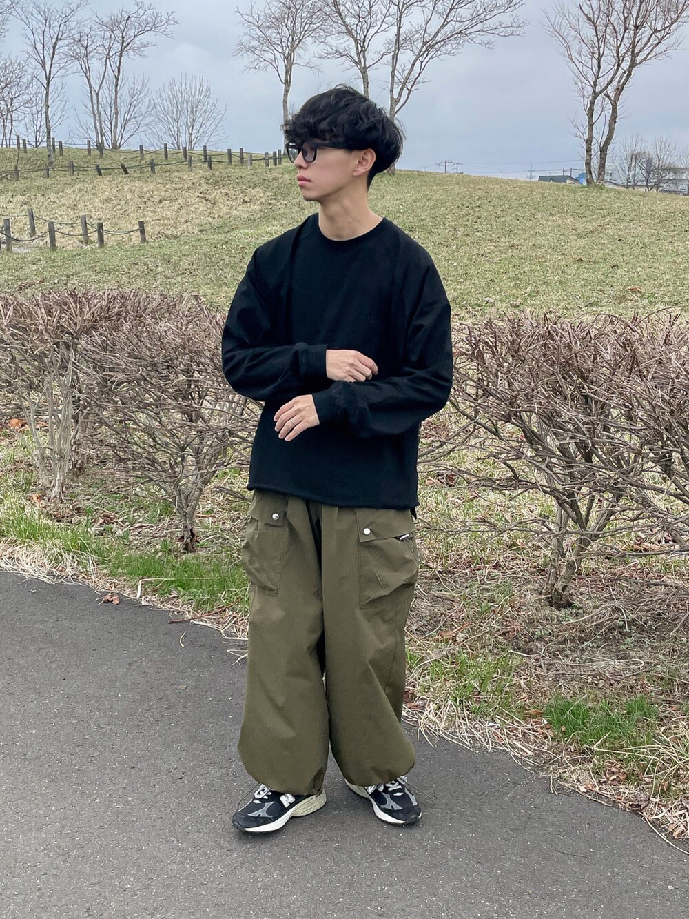 グレー系のベスト、ブラック系のTシャツ/カットソー、グリーン系のカーゴパンツを着用したメンズの春コーディネートの4枚目の写真