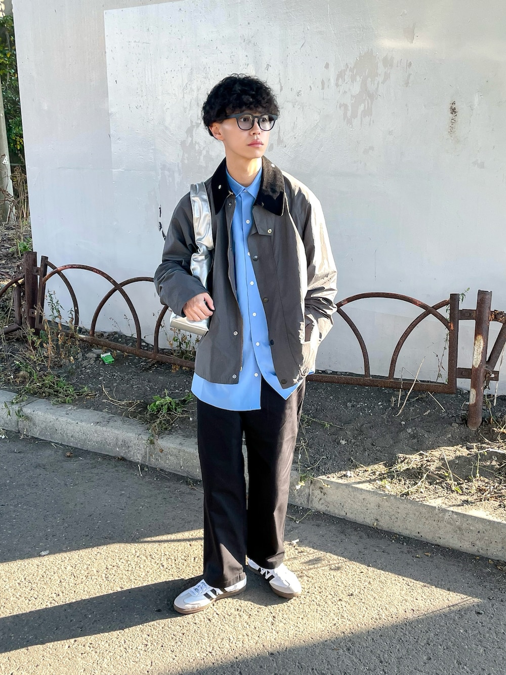 グレー系のナイロンジャケット、ブラック系のチノパンツ、ブルー系のシャツ/ブラウスを着用したメンズの秋コーディネートの2枚目の写真