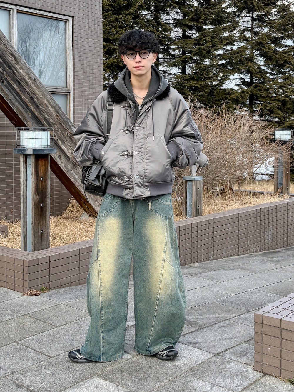 グレー系のパーカー、グレー系のブルゾン、ブルー系のデニムパンツを着用したメンズの冬コーディネートの2枚目の写真