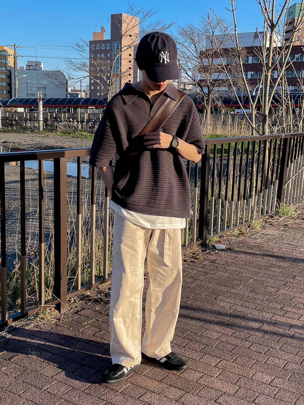 グレー系のポロシャツ、ホワイト系のタンクトップ、ホワイト系のデニムパンツを着用したメンズの春コーディネートの3枚目の写真