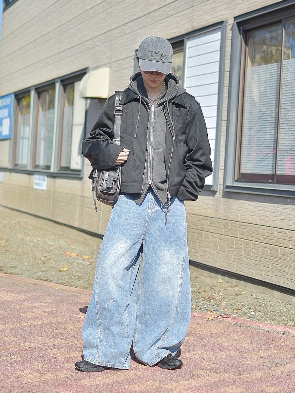 ブルー系のデニムパンツ、ブラック系のブルゾン、グレー系のパーカーを着用したメンズの秋コーディネートの4枚目の写真