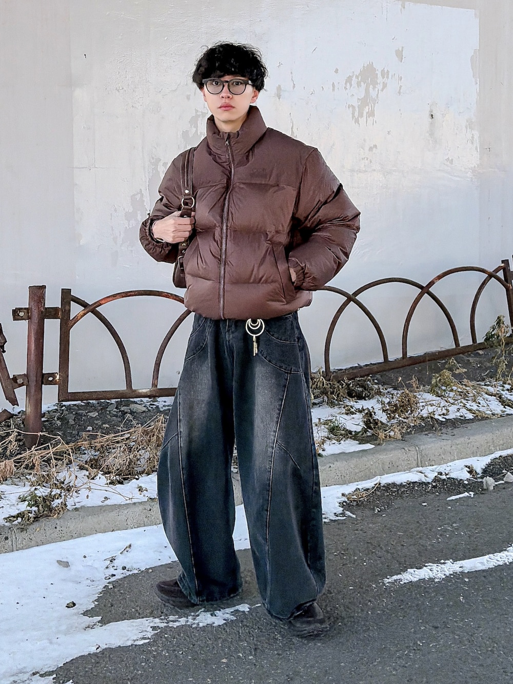 ブラウン系のダウンジャケット/コート、ブラック系のニット/セーター、ブラック系のデニムパンツを着用したメンズの冬コーディネートの4枚目の写真