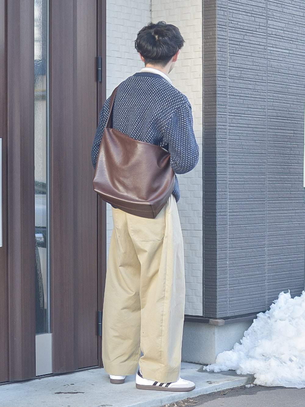 ブルー系のニット/セーター、ホワイト系のスニーカー、ブラウン系のショルダーバッグを着用したメンズの冬コーディネートの5枚目の写真