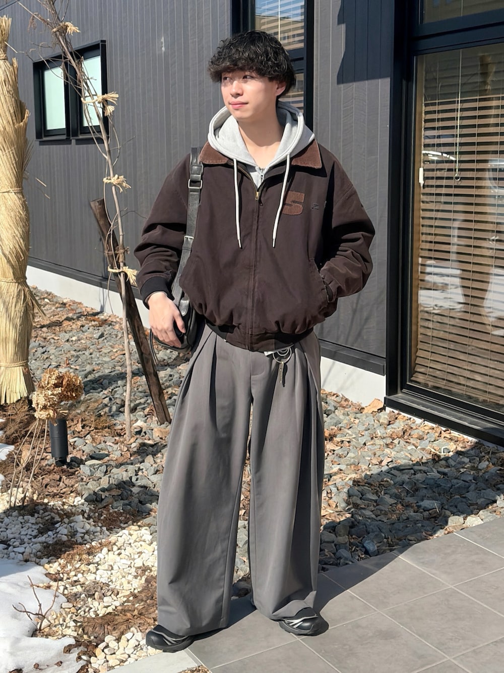 ブラック系のブルゾン、グレー系のパーカー、グレー系のスラックスを着用したメンズの春コーディネートの4枚目の写真