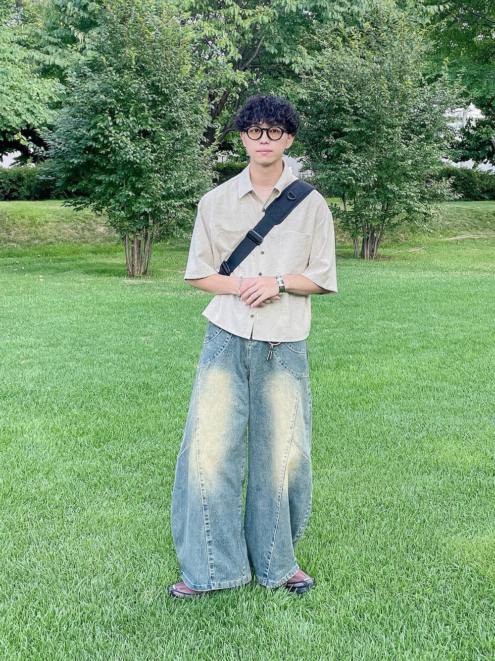 ブラウン系のスニーカー、ベージュ系のシャツ/ブラウス、ブルー系のデニムパンツを着用したメンズの夏コーディネートの3枚目の写真