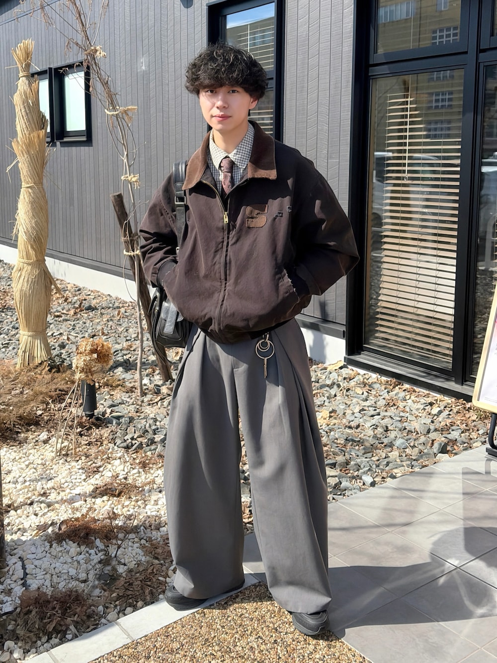 ブラック系のブルゾン、ホワイト系のシャツ/ブラウス、グレー系のスラックスを着用したメンズの春コーディネートの2枚目の写真