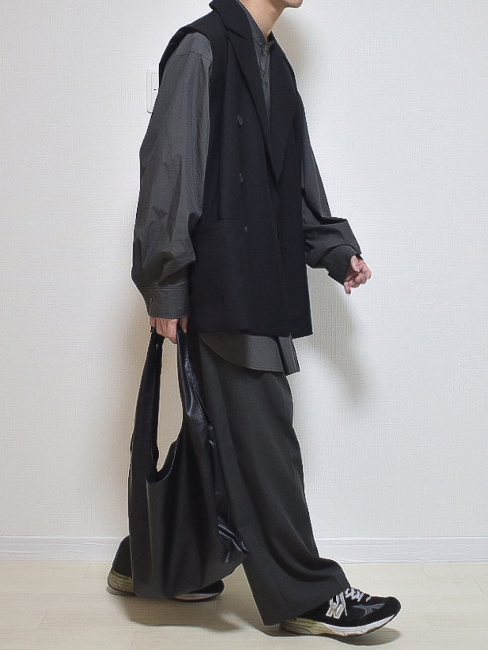 ブラック系のベスト、グレー系のスラックスを着用したメンズの秋コーディネートの2枚目の写真