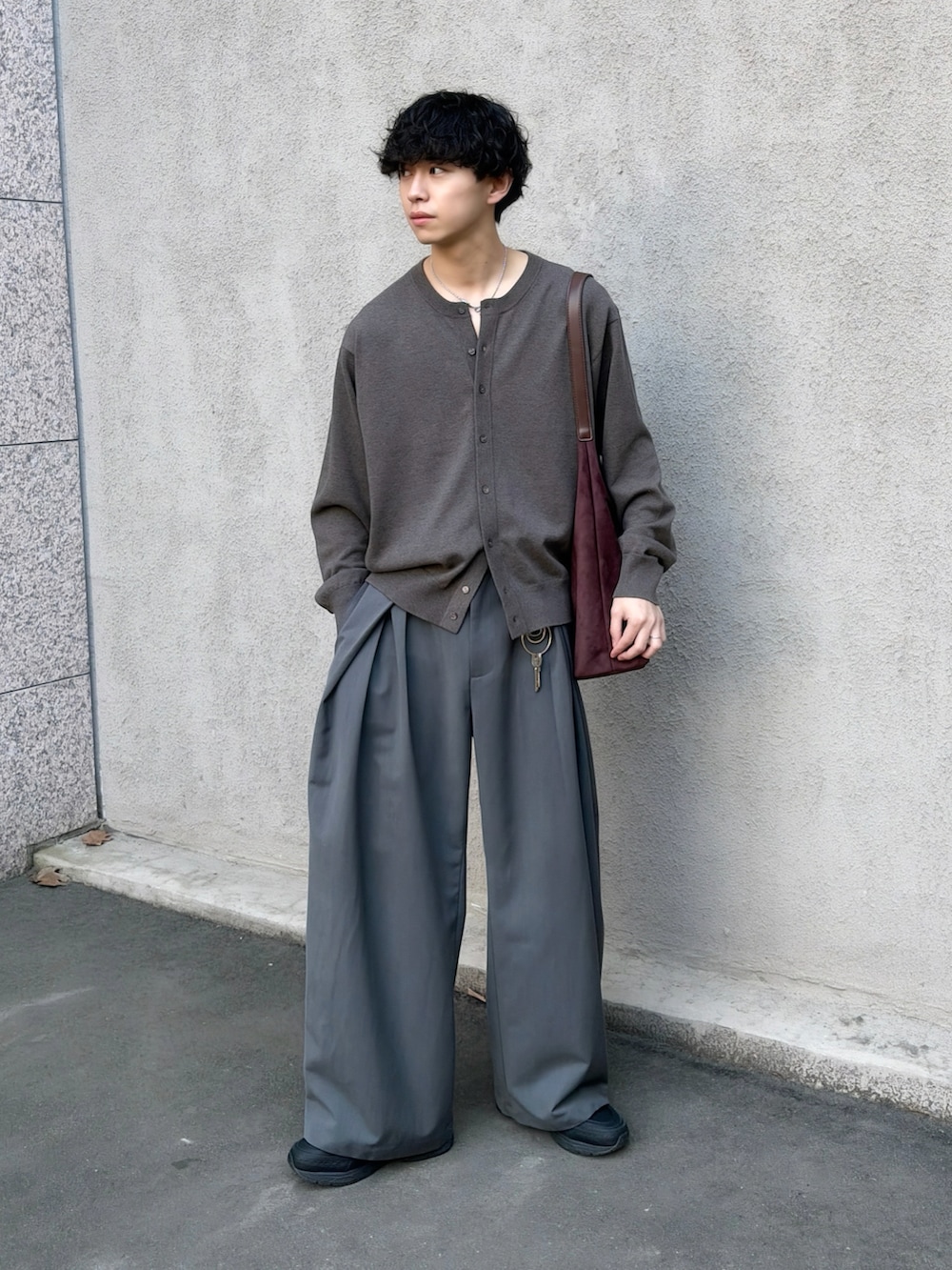 ブラウン系のカーディガン/ボレロ、グレー系のスラックス、ブラウン系のショルダーバッグを着用したメンズの春コーディネートの3枚目の写真