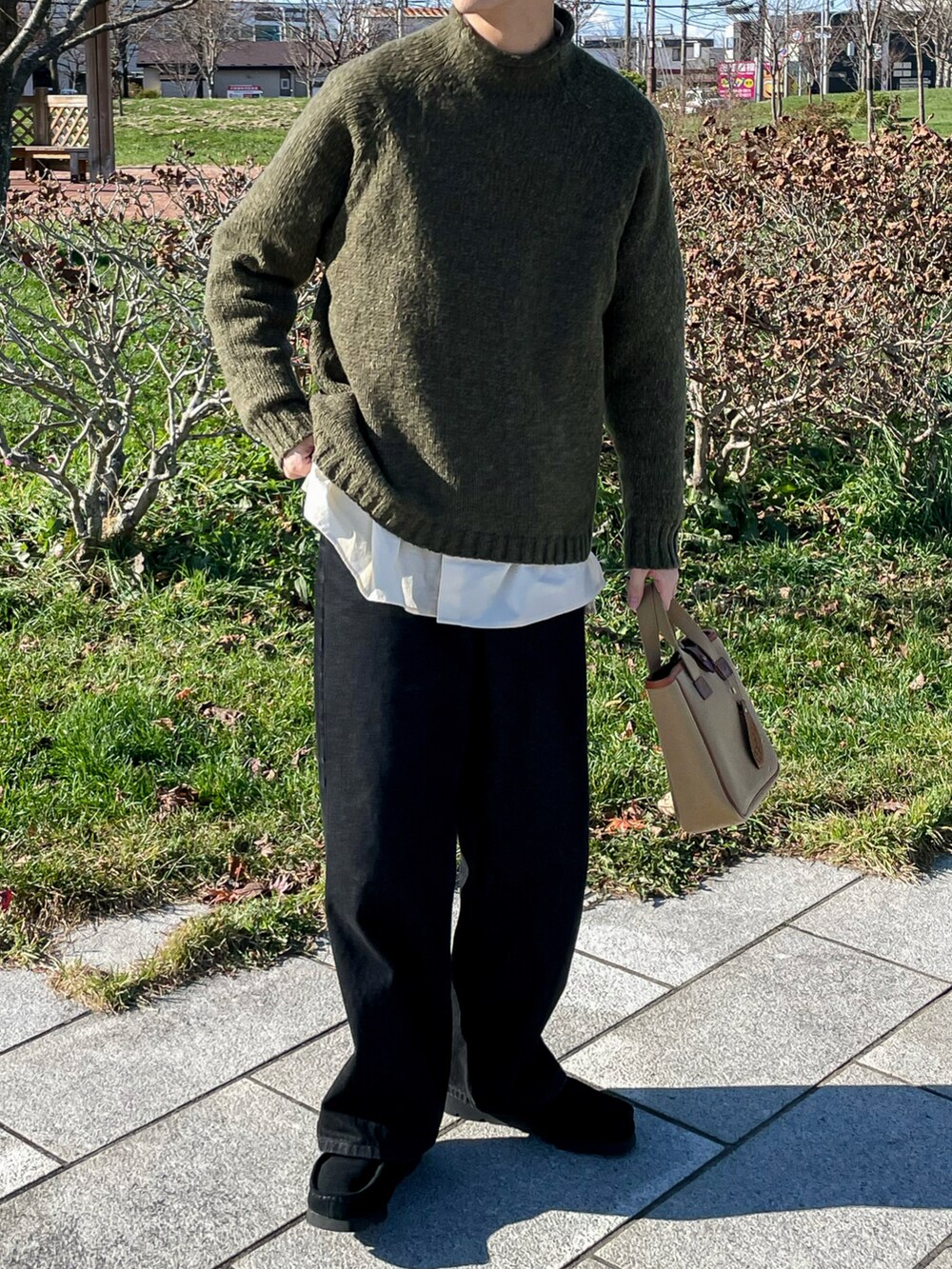 グリーン系のニット/セーター、ブラック系のデニムパンツ、ブラック系のモカシン/デッキシューズを着用したメンズの秋コーディネートの5枚目の写真