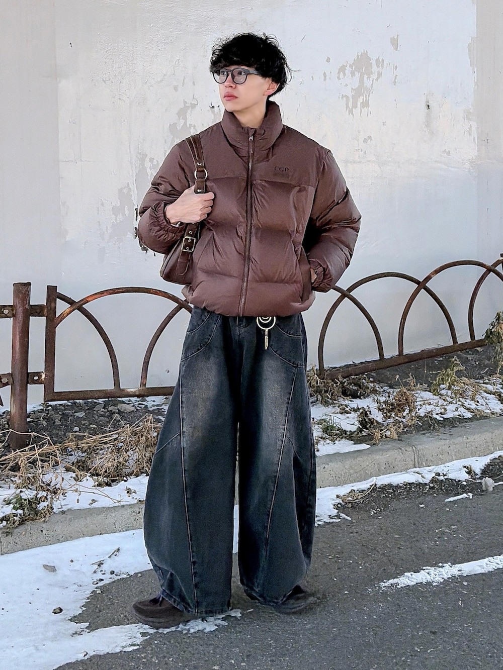 ブラウン系のダウンジャケット/コート、ブラック系のニット/セーター、ブラック系のデニムパンツを着用したメンズの冬コーディネートの3枚目の写真