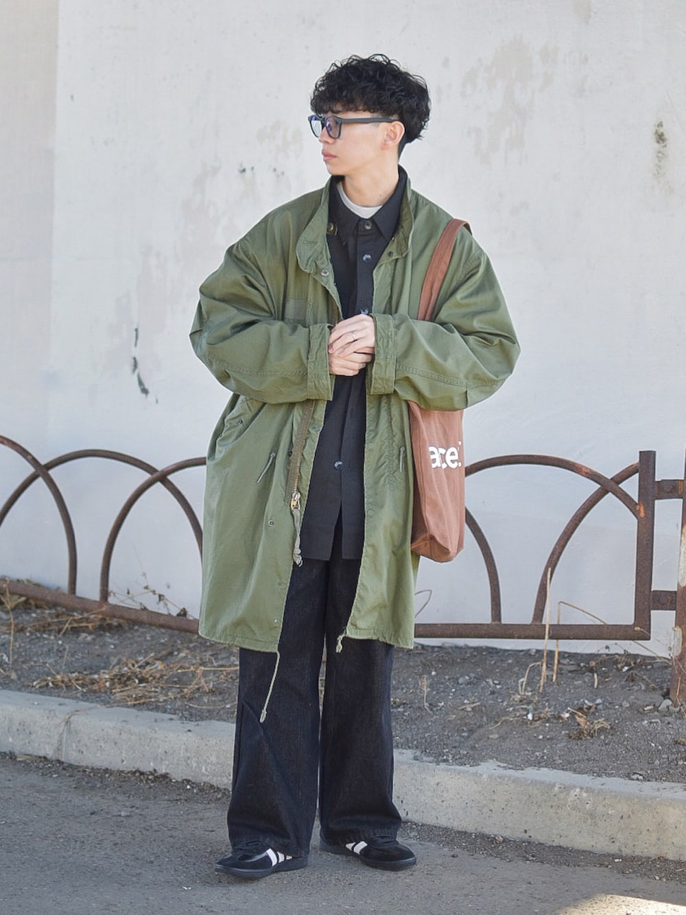 グリーン系のモッズコート、ブラック系のデニムパンツ、ブラック系のスニーカーを着用したメンズの冬コーディネートの2枚目の写真