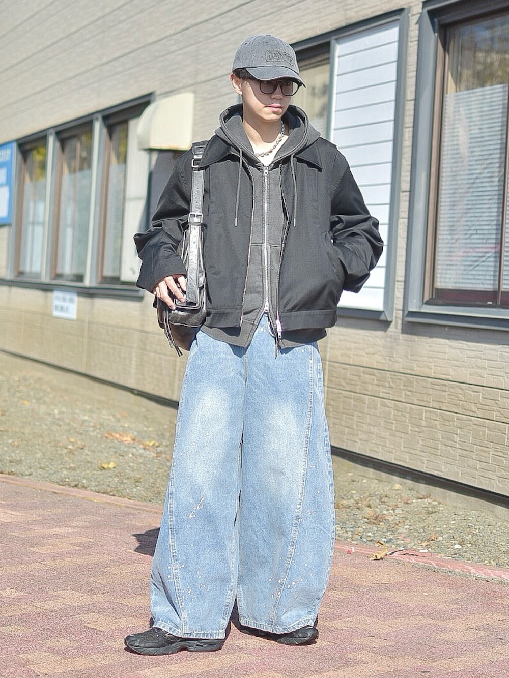 ブルー系のデニムパンツ、ブラック系のブルゾン、グレー系のパーカーを着用したメンズの秋コーディネートの3枚目の写真