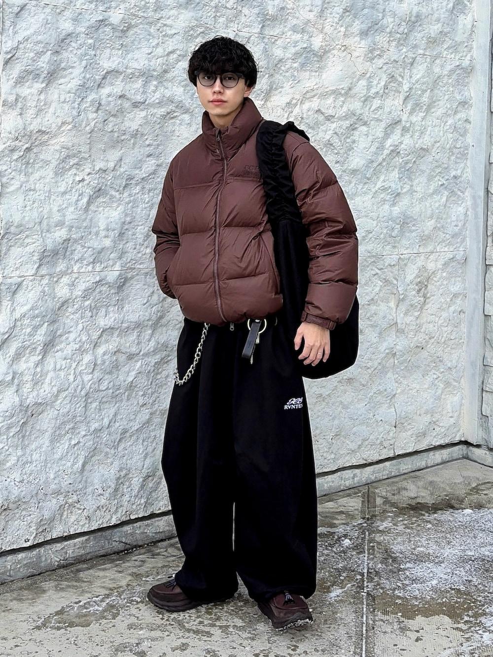 ブラック系のスウェットパンツ、ブラウン系のダウンジャケット/コート、ブラック系のショルダーバッグを着用したメンズの冬コーディネートの3枚目の写真