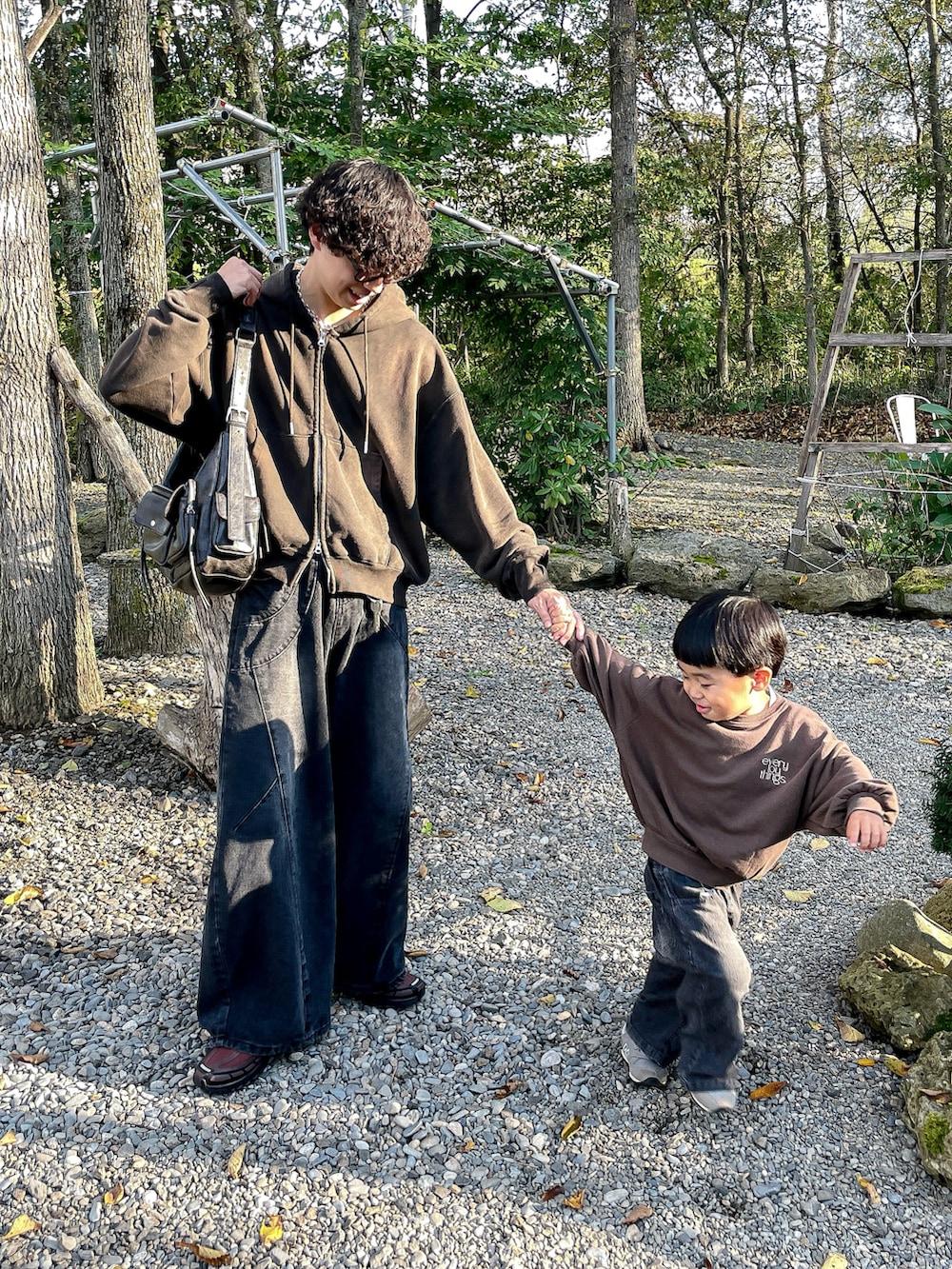 ブラウン系のパーカー、ブラック系のデニムパンツ、ブラウン系のスニーカーを着用したメンズの秋コーディネートの2枚目の写真