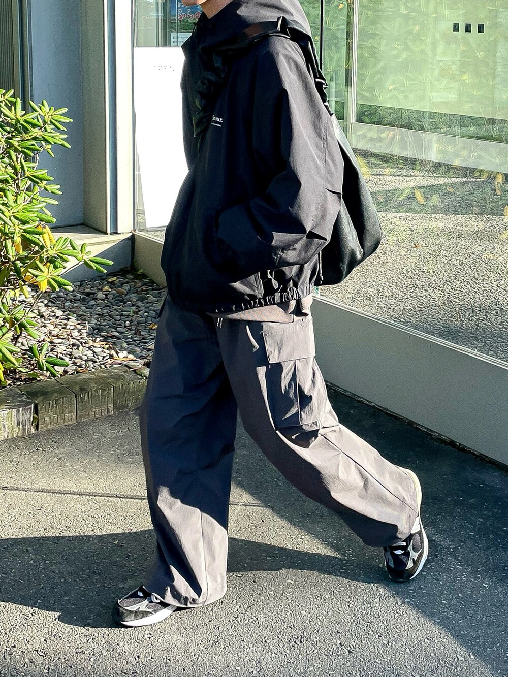ブラック系のナイロンジャケット、ブラウン系のカーゴパンツ、ブラック系のショルダーバッグを着用したメンズの秋コーディネートの4枚目の写真