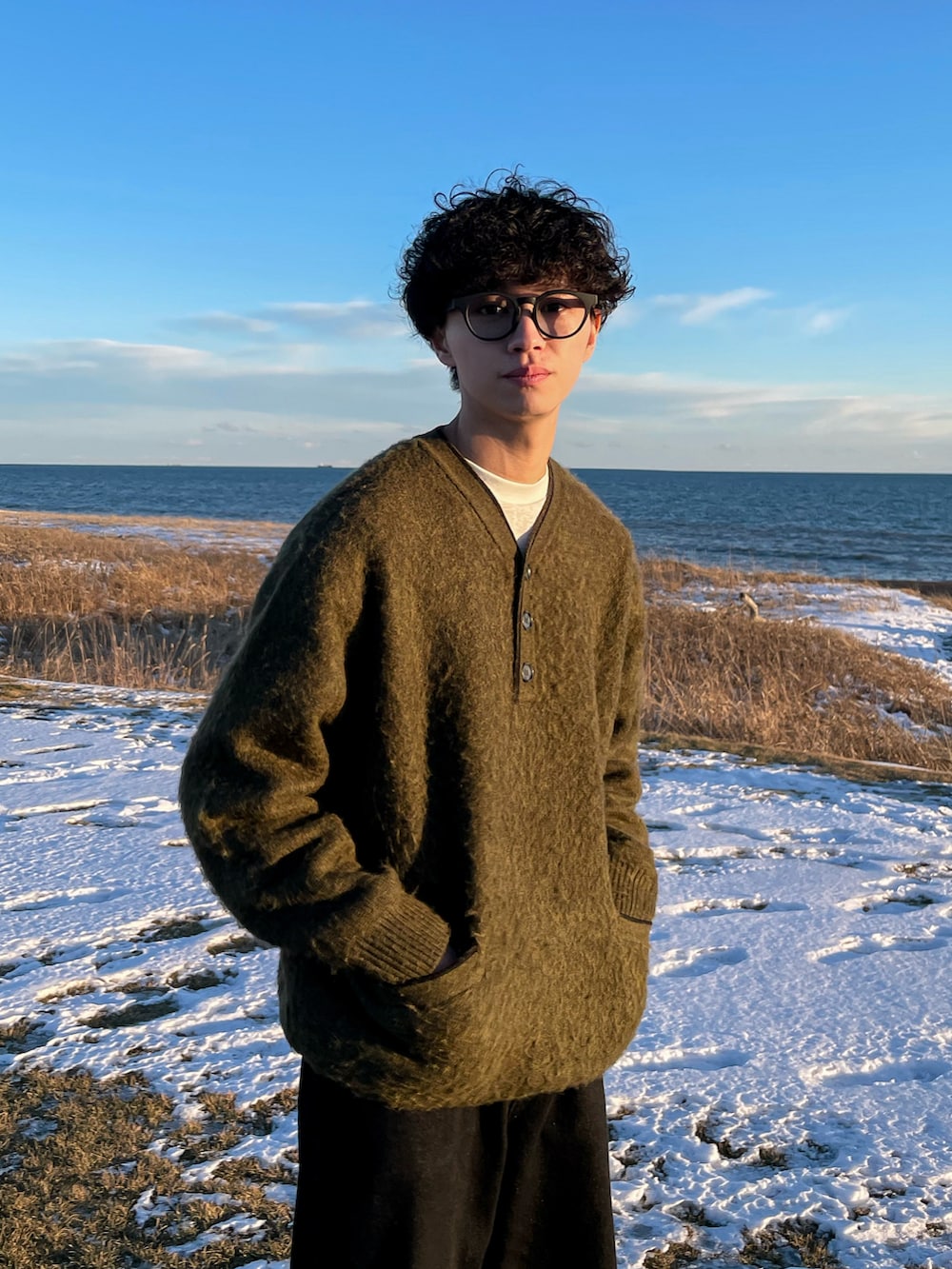 グリーン系のニット/セーター、グレー系のTシャツ/カットソー、ブラック系のデニムパンツを着用したメンズの冬コーディネートの4枚目の写真