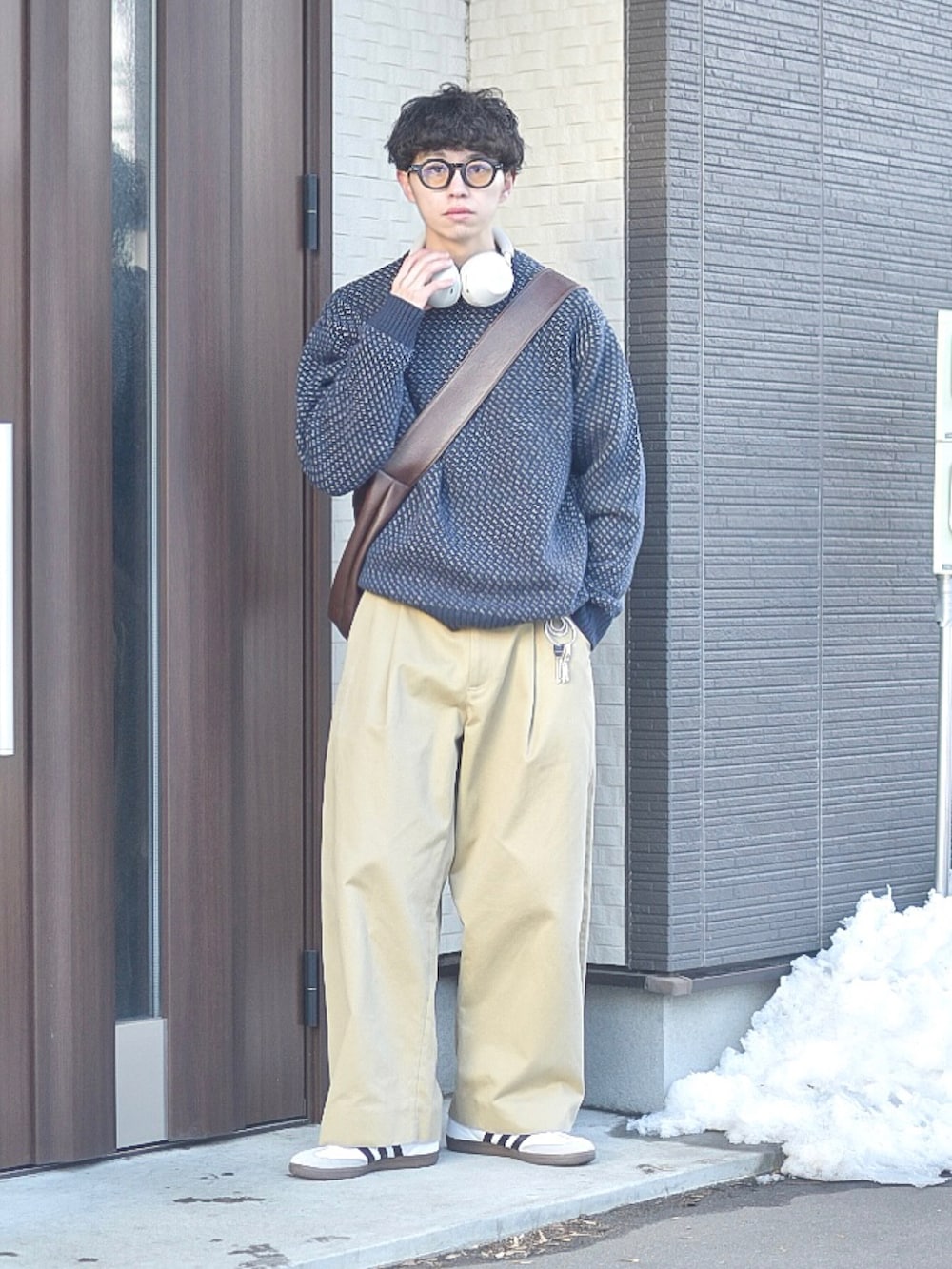 ブルー系のニット/セーター、ホワイト系のスニーカー、ブラウン系のショルダーバッグを着用したメンズの冬コーディネートの3枚目の写真