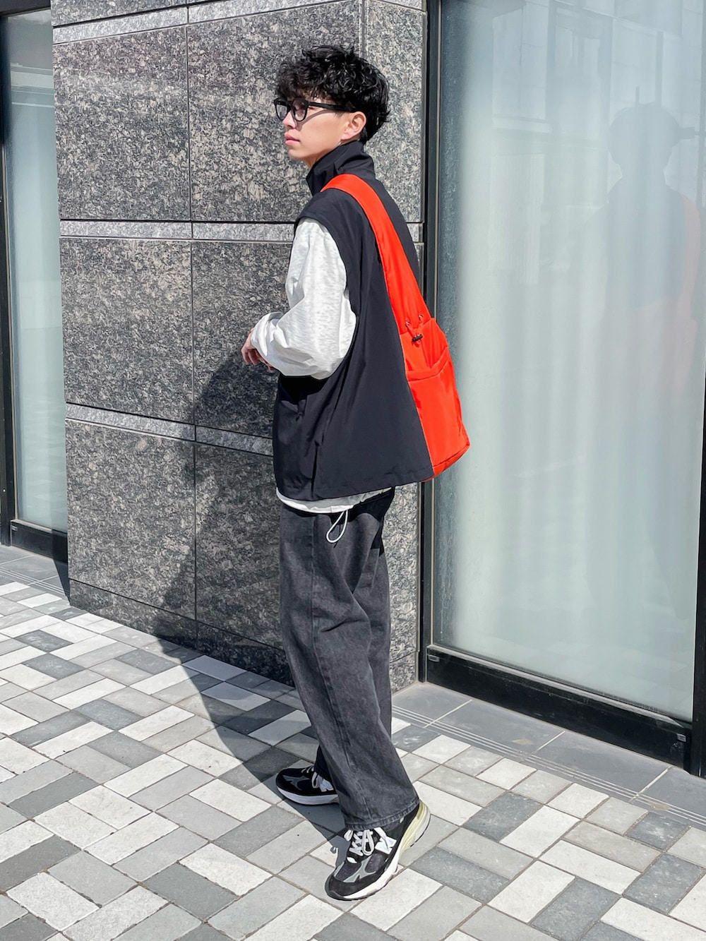 ブラック系のブルゾン、ブラック系のデニムパンツ、オレンジ系のショルダーバッグを着用したメンズの春コーディネートの4枚目の写真