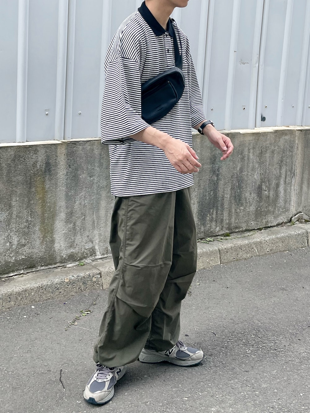 ブラック系のポロシャツ、ブラック系のボディバッグ/ウエストポーチ、グレー系のスニーカーを着用したメンズの夏コーディネートの3枚目の写真