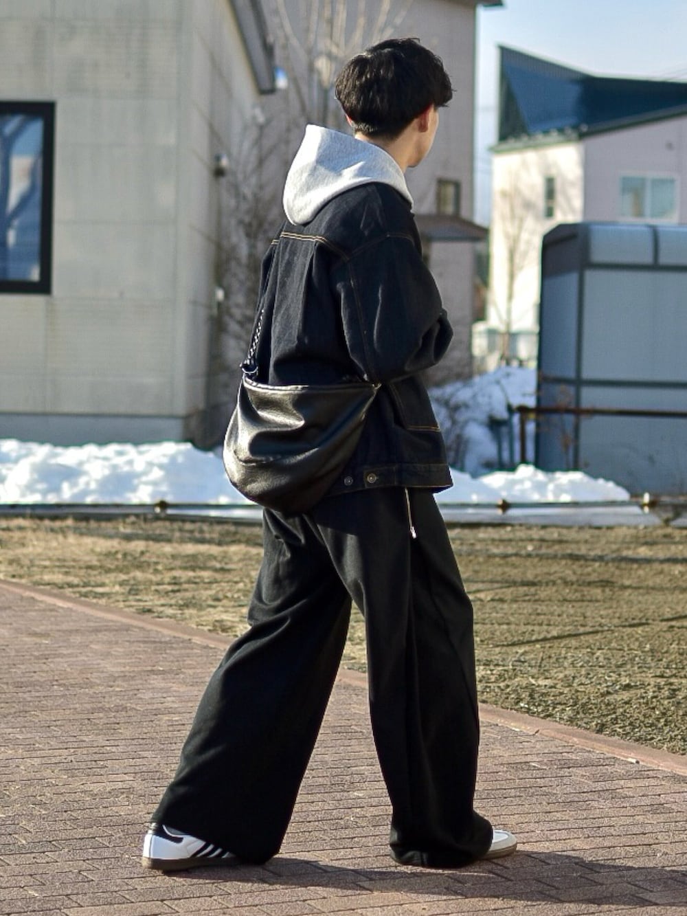 ブルー系のデニムジャケット、グレー系のパーカー、ブラック系のスウェットパンツを着用したメンズの春コーディネートの4枚目の写真