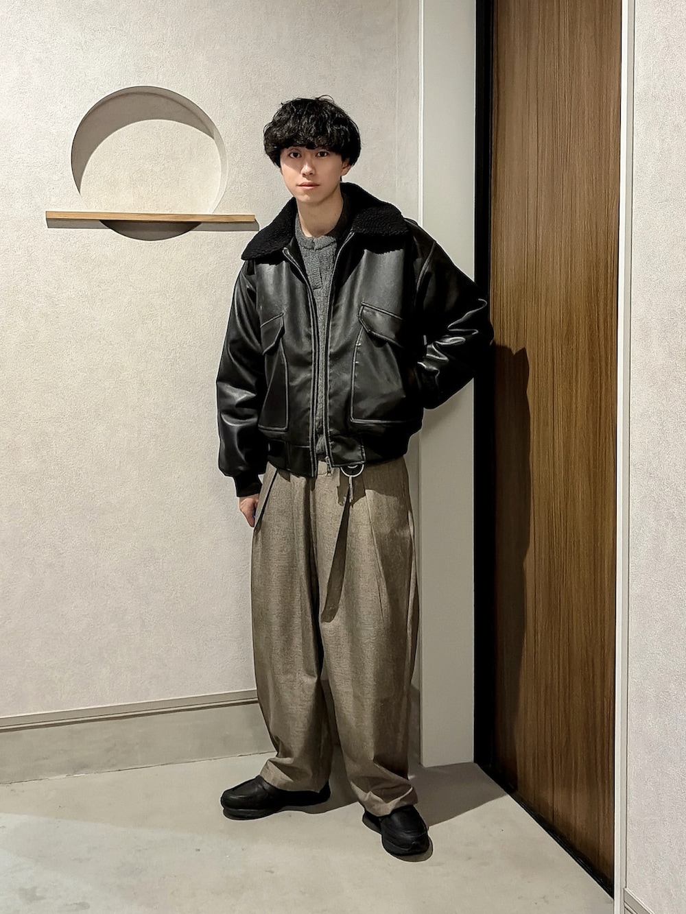 ブラック系のブルゾン、グレー系のニット/セーター、ブラウン系のスラックスを着用したメンズの冬コーディネートの4枚目の写真