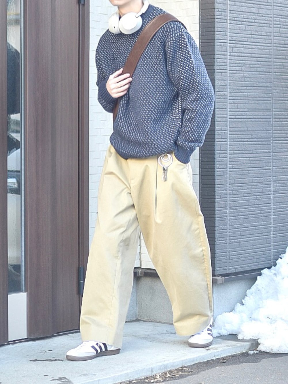 ブルー系のニット/セーター、ホワイト系のスニーカー、ブラウン系のショルダーバッグを着用したメンズの冬コーディネートの4枚目の写真