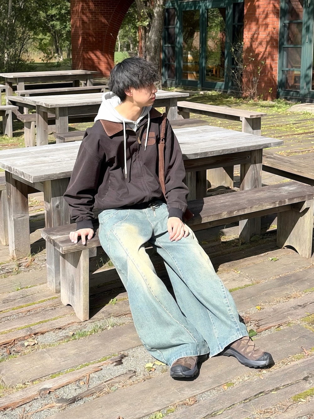 ブラック系のブルゾン、グレー系のパーカー、ブルー系のデニムパンツを着用したメンズの秋コーディネートの2枚目の写真