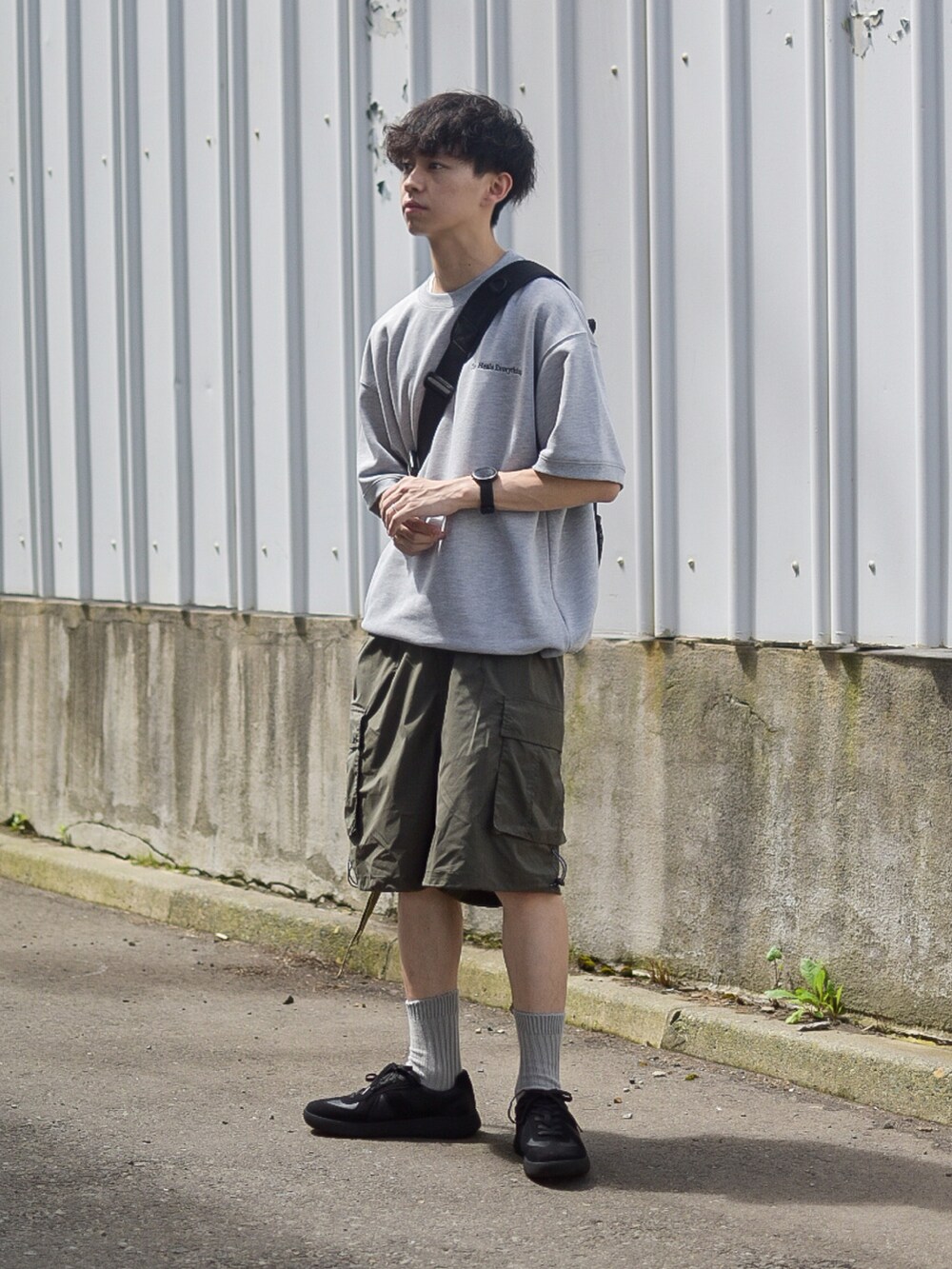グレー系のTシャツ/カットソー、グリーン系のカーゴパンツ、ブラック系のスニーカーを着用したメンズの夏コーディネートの2枚目の写真
