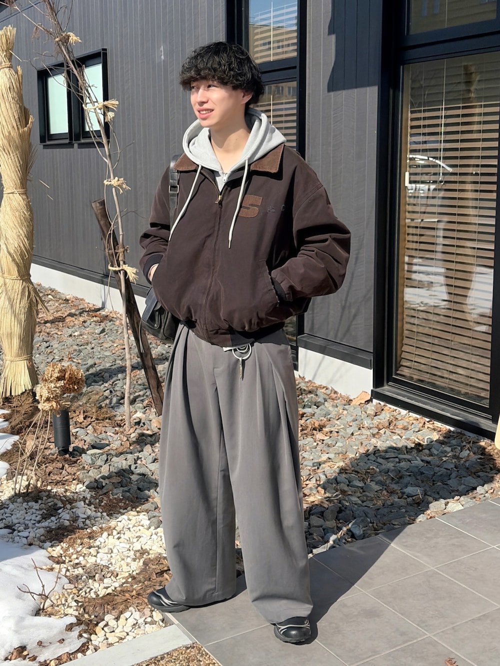 ブラック系のブルゾン、グレー系のパーカー、グレー系のスラックスを着用したメンズの春コーディネートの2枚目の写真