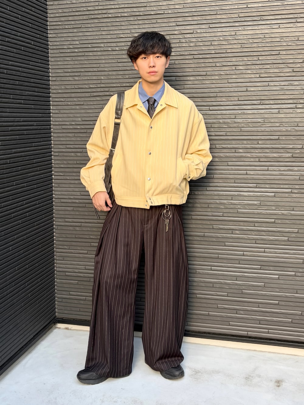 ブラック系のショルダーバッグ、ブルー系のシャツ/ブラウス、イエロー系のブルゾンを着用したメンズの春コーディネートの2枚目の写真