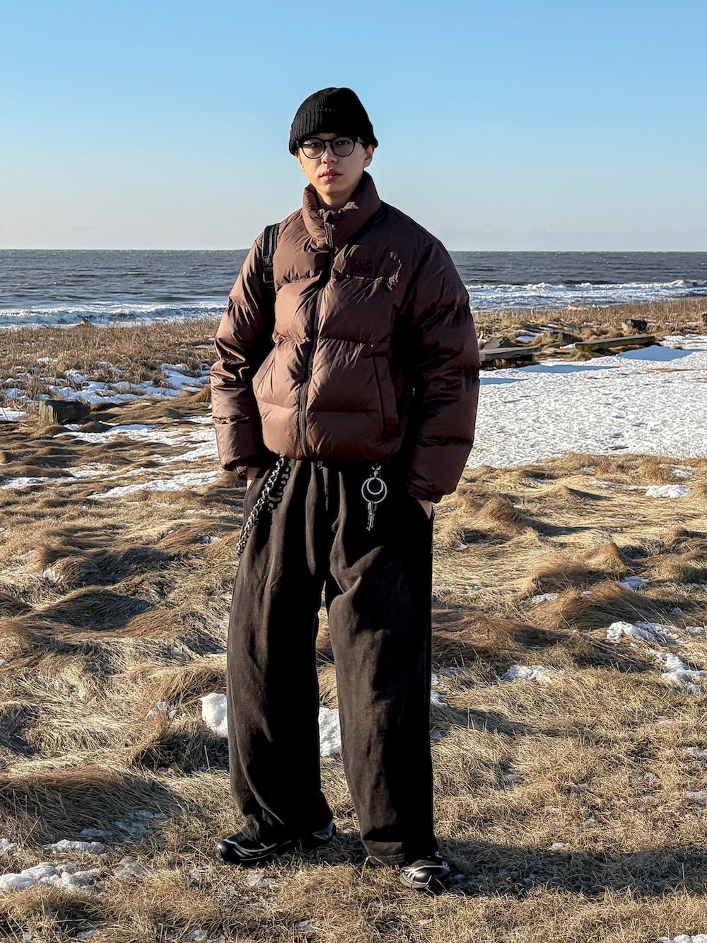 ブラウン系のダウンジャケット/コート、ブラック系のスウェットパンツ、ブラック系のスニーカーを着用したメンズの冬コーディネートの3枚目の写真