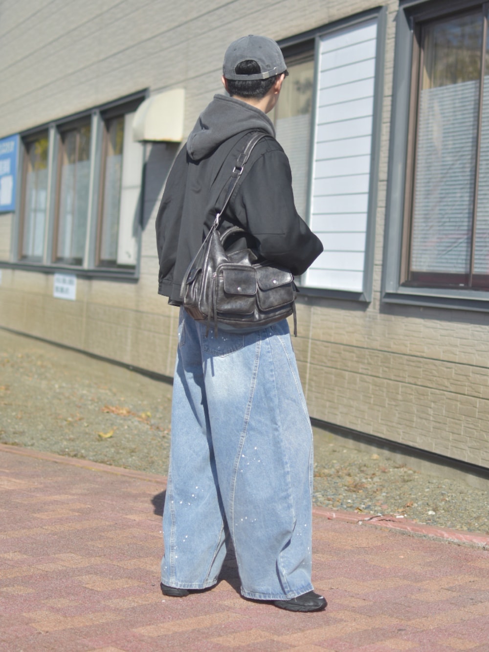 ブルー系のデニムパンツ、ブラック系のブルゾン、グレー系のパーカーを着用したメンズの秋コーディネートの5枚目の写真