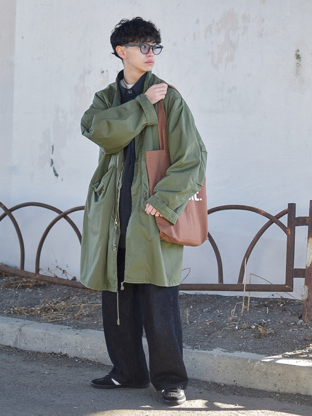 グリーン系のモッズコート、ブラック系のデニムパンツ、ブラック系のスニーカーを着用したメンズの冬コーディネートの3枚目の写真