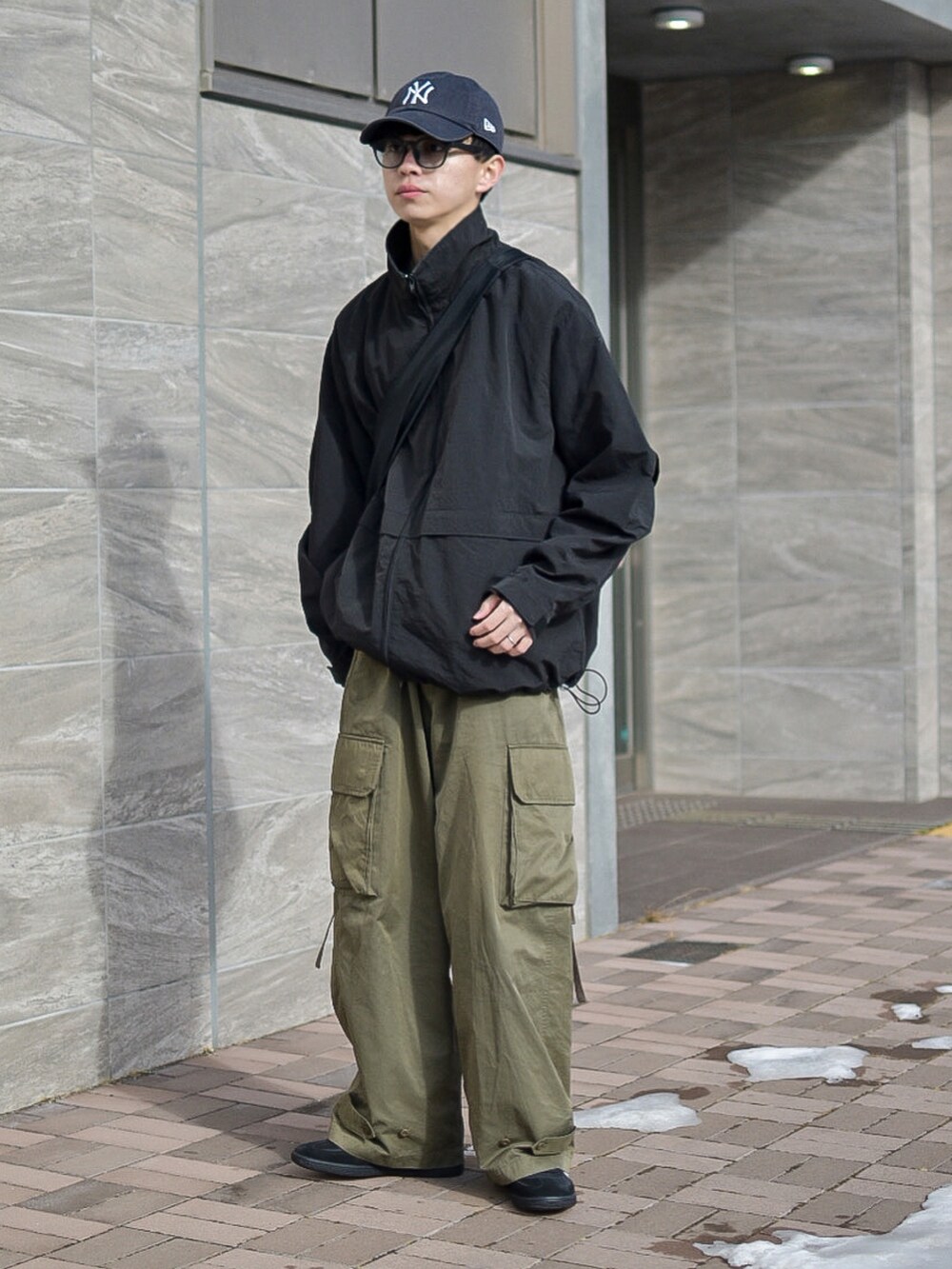 ブラック系のナイロンジャケット、グリーン系のカーゴパンツ、ブラック系のスニーカーを着用したメンズの冬コーディネートの2枚目の写真