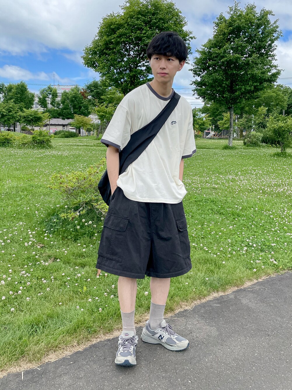 ホワイト系のトップス、ブラック系のパンツ、グレー系のスニーカーを着用したメンズの夏コーディネートの2枚目の写真